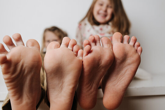 Children's bare feet close up to the camera. Their blurred giggling faces in a background.