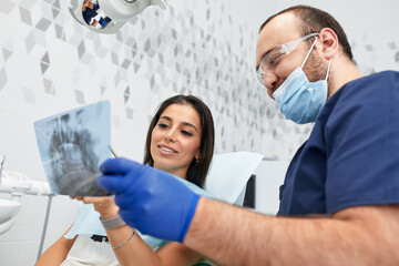 Fototapeta na wymiar people, medicine, stomatology and health care concept - happy male dentist showing work plan to woman patient at dental clinic office