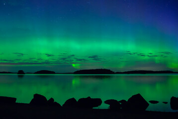 Fototapeta na wymiar Northern lights dancing over calm lake. Farnebofjarden national park in north of Sweden.