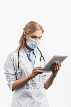 nurse in medical mask and white coat using digital tablet isolated on white, stock image