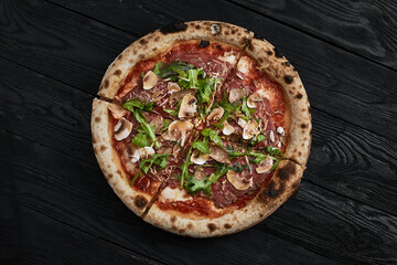 Close up on delicious freshly baked small pizza with melted cheese mushrooms and arugula