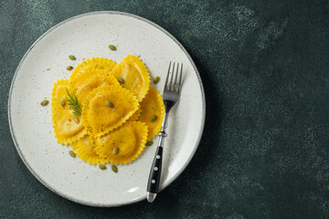 Homemade Pumpkin Ravioli with butter on a dark concrete background. Top view with copy space