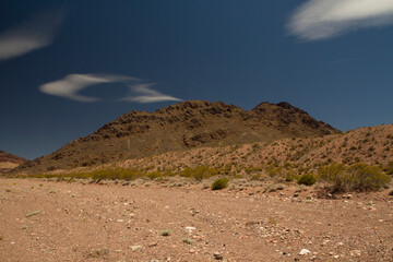 Desert landscape. View of the arid sand and rocky mountains under a deep blue sky. 