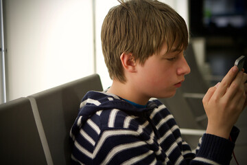 Teenage boy looking at smartphone in airport waiting lounge
