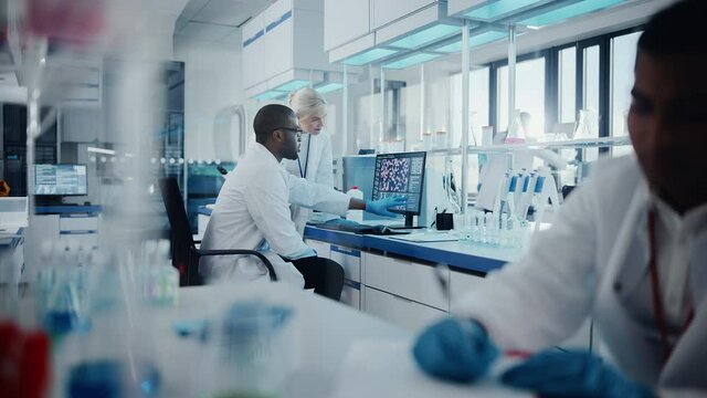 Modern Medical Research Laboratory: Two Scientists Working Together Analysing Samples, Discussing Innovative Technology. Advanced Scientific Lab for Medicine, Biotechnology, Molecular Biology 