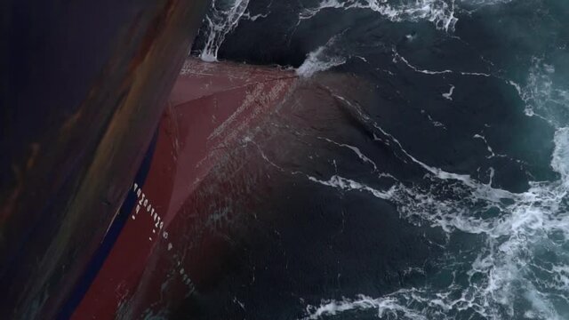 The bow of the ship is immersed in dark sea water.