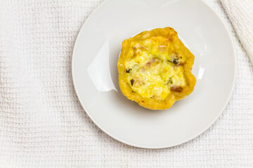 Mini quiche with bacon, egg, cheese and parsley on white - single tartlet with copy space