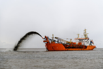 Vessel engaged in dredging. Dredger working at sea. Ship excavating material from a water environment.