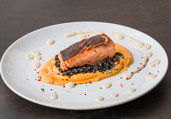 Plate with salmon fish fillet, sweet potato puree, quinoa and creamy sauce. Fresh food close-up