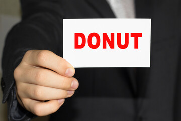 Card with text DONUT on hand. You can use in business, marketing and other concepts. Messege of the day.