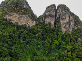 Fototapeta na wymiar AERIAL: Breathtaking aerial view of the tall mountains covered by the tropical forest towering over the empty valley in the heart of exotic island.