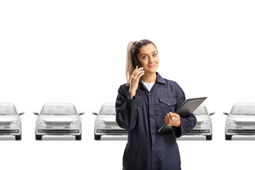 Female auto mechanic in a car showroom talking on a mobile phone