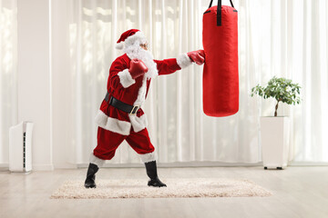 Full length profile shot of santa claus punching a boxing bag
