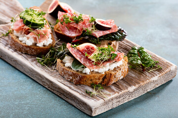 Variety of mini sandwiches with cream cheese, vegetables and salami.