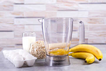 Oat pancakes with banana. Step by step cooking process. Ingredients top view. Bananas, milk, eggs, oats, salt. Wooden table background. Copy space