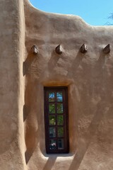 Obraz premium Native American Adobe house wooden window in Santa Fe, New Mexico with wood beams, built of a material mix of earth and straw.