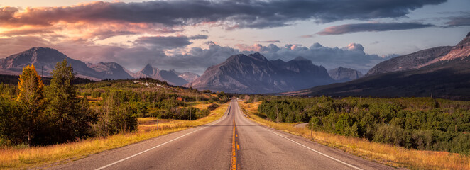 Beautiful View of Scenic Highway with American Rocky Mountain Landscape in the background. Colorful Summer Sunrise Sky. Taken in St Mary, Montana, United States. - obrazy, fototapety, plakaty