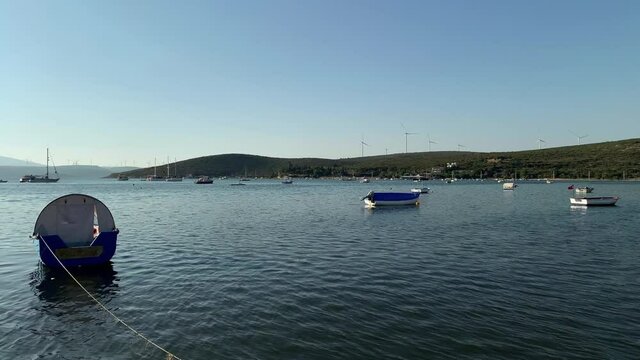 Footage of moored fishing boats and yachts, windmills farm in famous, touristic Aegean town called "Sigacik". It is a village of Seferihisar district of Izmir / Turkey. It is a sunny summer day.
