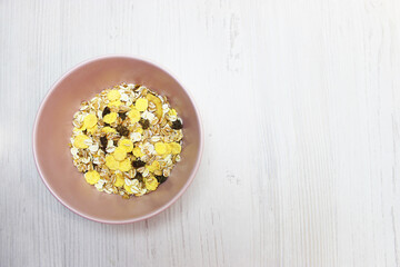 muesli with on a pink plate, top view. Muesli with fresh milk, yogurt or kefir. Muesli is made from oatmeal, a mixture of multi-grain flakes with dried fruits, nuts and sunflower seeds. on a white