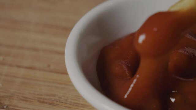Dipping fresh fast food  french fries in ketchup