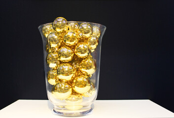Gold colored christmas tree balls in a jar with great contrast against a dark background
