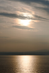 Sunset at Garda lake, Italy. Sun behind clouds with reflections. 
