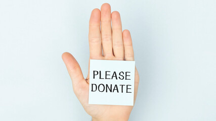 holding a white paper with please donate text