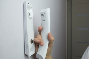 Naklejka premium woman who uses a home intercom to let a guest or family member into her apartment