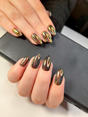 Bright iridescent gel polish with multicolored highlights. Women's hands with long almond-shaped...