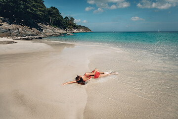 Fototapeta na wymiar Female in red bikini and sunglass lying on the beach, seductive female in swimsuit rest after swimming. Phuket. Thailand