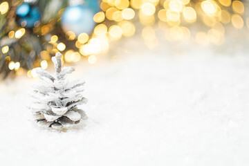 Pine cones on the snow with Christmas decoration on the background with copy space.