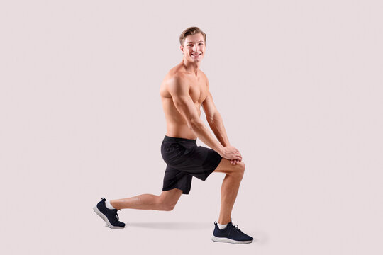 Energetic young athlete warming up before strength workout over light studio background, full length portait