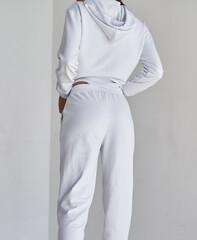 woman stands in white pants from behind. sporty girls wears tight textile trousers