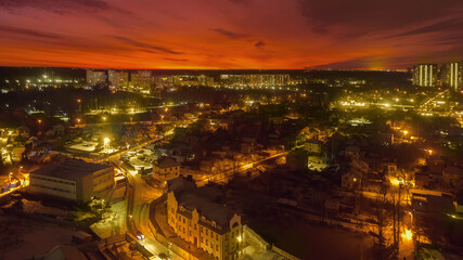 Red sunrise on the cityscape. Detailed view of buildings and streets in the dark red colors. Panoramic picture of early morning from abstract world.