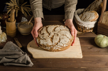 A woman serves freshly baked home-baked whole grain rye bread.