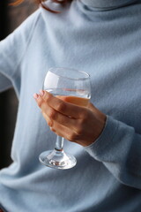 a glass of water in the hands of a girl in a blue sweater