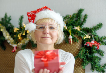 Smiling middle - aged woman in Santa hat. Remote congratulations on Christmas.