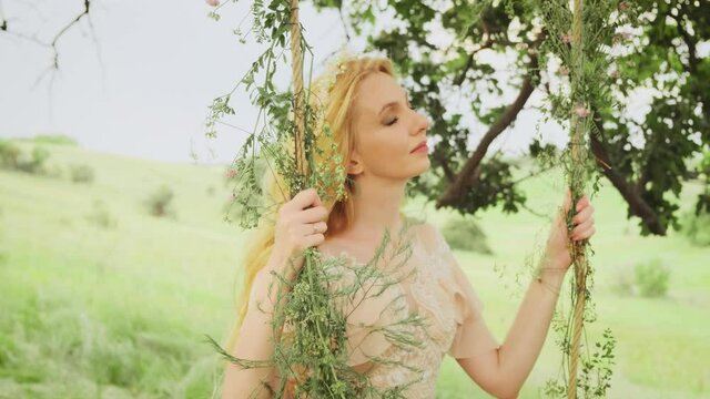 Portrait of young beautiful woman with natural blond long hair flying in wind. Cute face of blonde girl in the image of a forest princess gentle shy smile. Background summer, green, spring nature