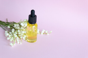 Dropper bottle glass . Oil cosmetics for skin care makeup. Spring bouquet of lilies of the valley.