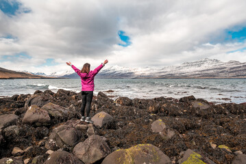 positive woman with hands high up in the air enjoying the view of Iceland
