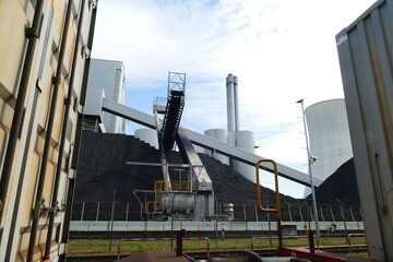 Coal dumps behind two railway cars and in front of the coal-fired power plant in Hanover-Stöcken, Lower Saxony, Germany.