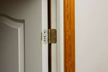 Close up view of open white door  with retro gold door hinge. 