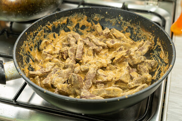 Liver stewed in sour cream in a frying pan.