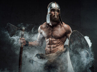 Scandinavian armoured nord warrior with naked torso and muscular build posing holding his shield...