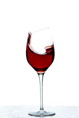 Close up view of splashing red wine in glass isolated on white background. 