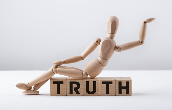 Wooden man sits on wooden cubes with the text TRUTH.