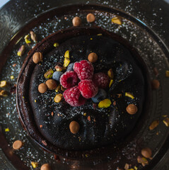 Chocolate cheesecake with raspberries, blueberries, pistachios and gold chocolate on a arabic decorated plate