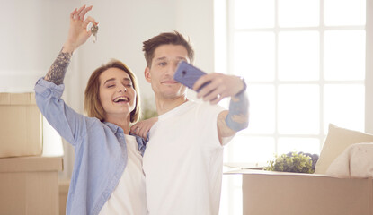 Obraz premium Happy smiling young couple showing a pair of keys of their new house