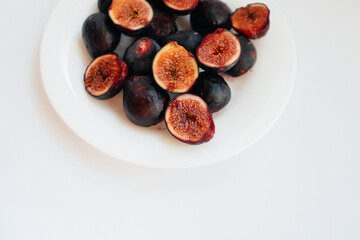 Ripe and sweet figs cut and arranged in a plate on a white background with free space. Fruits and vegetarianism