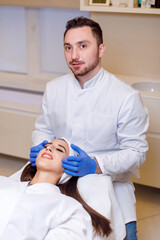 Doctor makes a markup on the face of a beautiful female before the comet procedure for correcting...